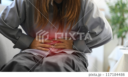 Young woman holding belly suffering from stomachache, diarrhea, food poisoning or menstrual period Young woman holding belly suffering from stomachache, diarrhea, food poisoning or menstrual period 117184486