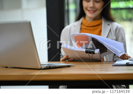 Asian female financier worker using laptop and checking statistic report at office desk 117184539