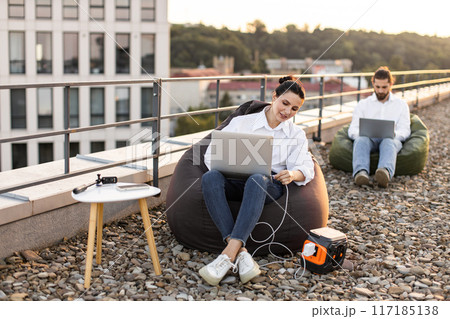 Business professionals working outdoors on rooftop with laptops 117185138