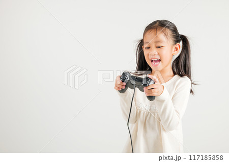 Asian happy portrait young kid girl smile lifestyle games technology holding joystick game playing on hands studio shot isolated white background with copy space, kindergarten child relaxation time 117185858