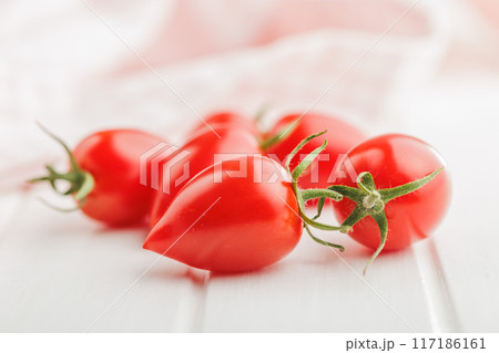 Red cherry tomatoes on white table. 117186161