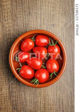 Red cherry tomatoes in bowl on wooden table. Top view. Red cherry tomatoes in bowl on wooden table. Top view. 117186173