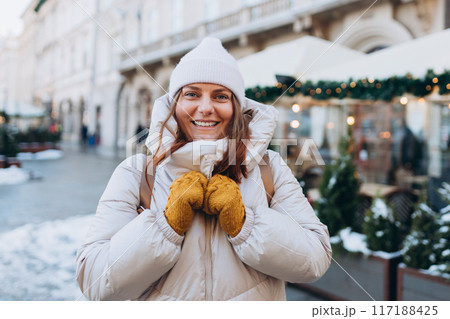 Happy 30s woman posing on urban background on winter snowy day. Winter holidays banner. Concept of vacations, holidays and happiness Christmas. High quality photo 117188425