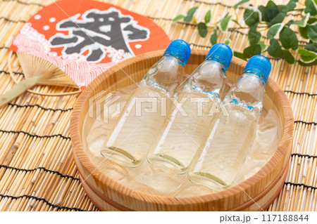 水と氷の入った桶で冷やされるラムネとお祭りの団扇 117188844