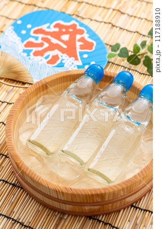 水と氷の入った桶で冷やされるラムネとお祭りの団扇 117188910