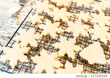 Letting delightful snowflake-shaped sugar cookies cool on a rack, preparing them for festive Christmas gifts. 117189104