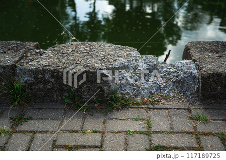 A broken concrete curb by the river. An old, ruined curb A broken concrete curb by the river. An old, ruined curb 117189725