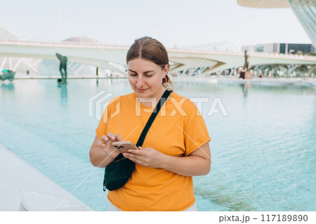 Young traveling woman using phone outdoors. Concept of travel, tourism and vacation in city. Ciudad de las Artes y las Ciencias de Valencia.Valencia City of Arts and Sciences. High quality photo Young traveling woman using phone outdoors. Concept of travel, tourism and vacation in city. Ciudad de las Artes y las Ciencias de Valencia.Valencia City of Arts and Sciences. High quality photo 117189890