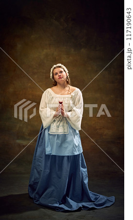 Cubby woman in traditional dress stands gracefully, holding glass of wine, her expression serene against vintage background. Festive celebration with elegance. 117190643