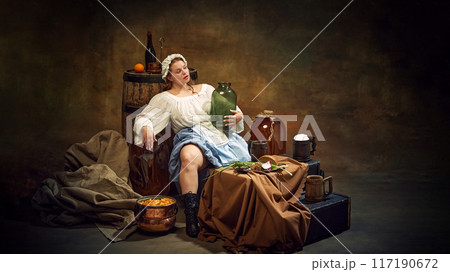 Woman in traditional attire relaxes with jug in hand, surrounded by rustic items like barrels, and simple food in tranquil, homely atmosphere. 117190672