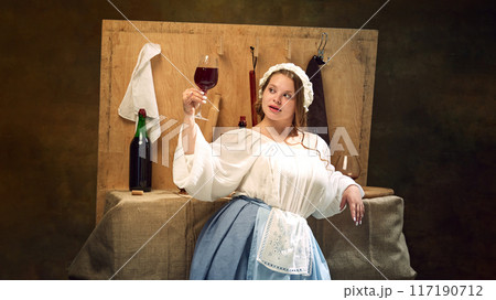 Young chubby medieval woman in vintage clothes holding glass of wine standing at ancient bar counter and enjoy evening. 117190712