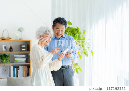 リビングでスマホを見るシニア夫婦 117192331