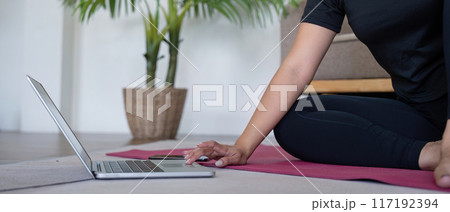 Woman Practicing Yoga at Home with Laptop, Indoor Exercise, Healthy Lifestyle, Relaxation, and Meditation Woman Practicing Yoga at Home with Laptop, Indoor Exercise, Healthy Lifestyle, Relaxation, and Meditation 117192394