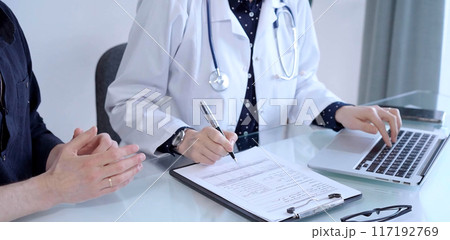 Doctor and patient are talking in clinic after usual health check up. Female physician is making notes and using laptop computer. Medicine concept Doctor and patient are talking in clinic after usual health check up. Female physician is making notes and using laptop computer. Medicine concept 117192769