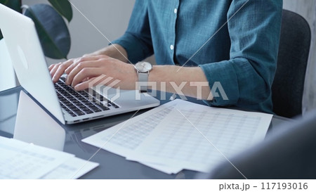 Professional casual dressed businessman is working on laptop at office grey and glass desk. Close-up of an adult's hands typing on a keyboard. Business people 117193016
