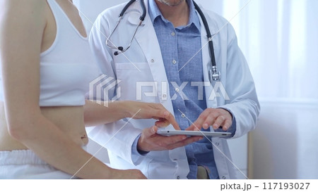 Doctor and patient. Physician is making notes on a clipboard while patient woman is describing something. Medicine concept 117193027