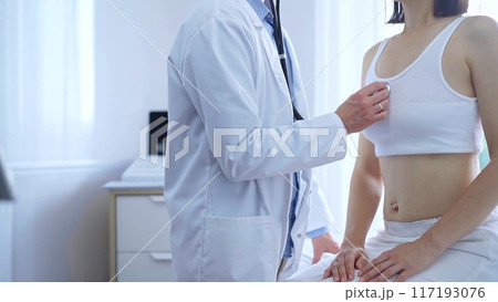 Doctor and patient. Physician is using stethoscope examining woman lungs in clinic cabinet. Medicine and health care Doctor and patient. Physician is using stethoscope examining woman lungs in clinic cabinet. Medicine and health care 117193076