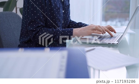 Female accountant or businesswoman is typing on laptop computer on glass desk in the office. Business people concept 117193286
