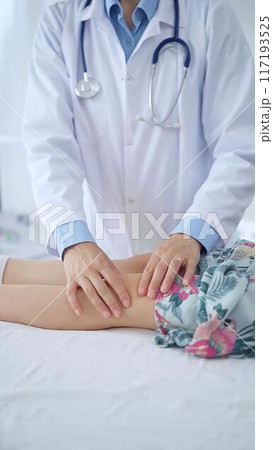 Doctor and kid patient. Orthopedist examining girl's knee in medical clinic. Medicine and health care 117193525