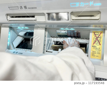 ATM機械にお札を入れる高齢女性の手元 ATM機械にお札を入れる高齢女性の手元 117193548