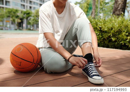 Tying Shoes Next to Basketball on Wooden Deck Tying Shoes Next to Basketball on Wooden Deck 117194993