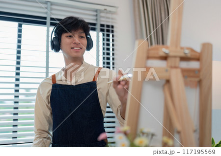 Young Artist Painting on Canvas with Headphones in Modern Studio 117195569
