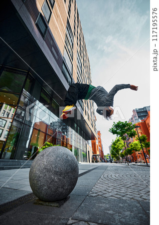 Parkrunner doing salto against city backdrop, showcasing athleticism and excitement amidst towering buildings and modern architecture. Parkrunner doing salto against city backdrop, showcasing athleticism and excitement amidst towering buildings and modern architecture. 117195576