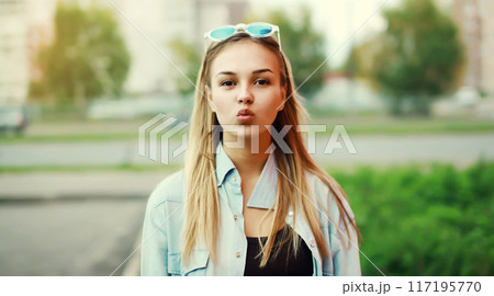 Portrait of beautiful young woman blowing a kiss posing on a summer day 117195770
