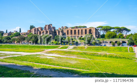 A view of the Domus Severiana ruins on Palatine Hill from Circus Maximus in Rome, Italy. The ancient Roman palace is visible in the distance, with a grassy area in the foreground. A view of the Domus Severiana ruins on Palatine Hill from Circus Maximus in Rome, Italy. The ancient Roman palace is visible in the distance, with a grassy area in the foreground. 117196436