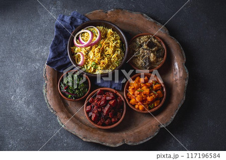 An assortment of vibrant, flavorful vegetarian Pakistani and Indian dishes, including biryani rice, served in bowls on a rustic platter An assortment of vibrant, flavorful vegetarian Pakistani and Indian dishes, including biryani rice, served in bowls on a rustic platter 117196584