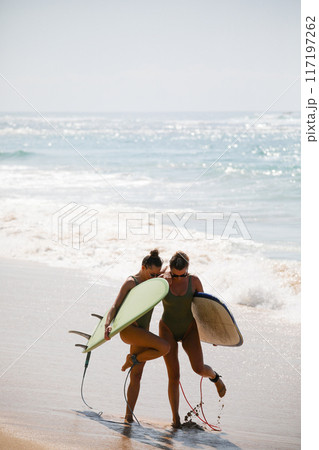 Two beautiful blondes in swimsuits pose with surfboards on the beach 117197262