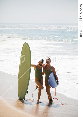 Two beautiful blondes in swimsuits pose with surfboards on the beach 117197279