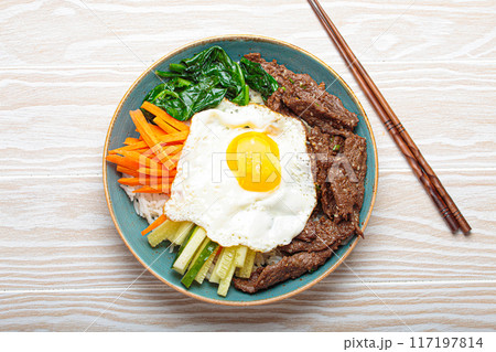 Traditional korean dish bibimbap with fried egg on top, top view on white wooden background 117197814