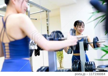 ジムで体を鍛える女性の背中　バーベルプレート　ウェイト選び　筋トレ女子　ワークアウト　 117198064