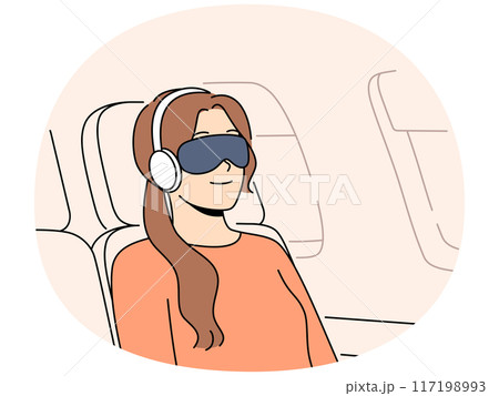 Young woman passenger flight with blindfold and earphones sleeps in airplane chair 117198993
