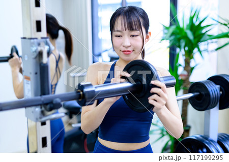 ジムで体を鍛える女性 バーベルプレート ウェイト選び 筋トレ女子 ワークアウト ジムで体を鍛える女性 バーベルプレート ウェイト選び 筋トレ女子 ワークアウト 117199295