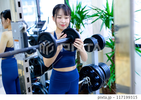ジムで体を鍛える女性　バーベルプレート　ウェイト選び　筋トレ女子　ワークアウト　 117199315