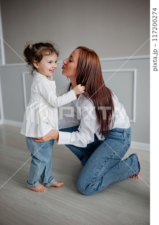 Happy young adult mom holding her adorable child girl  117200274