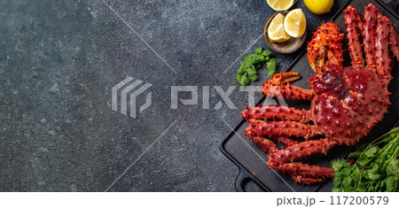 Vibrant king crab and assorted lemon slices arranged on a dark, rustic slate surface, cilantro, dark textured background, copy space, top view Vibrant king crab and assorted lemon slices arranged on a dark, rustic slate surface, cilantro, dark textured background, copy space, top view 117200579