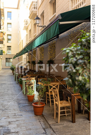 Outdoor street cafe tables ready for service. Empty cafe terrace with wooden tables and chairs, morning time. Food concept 117200668