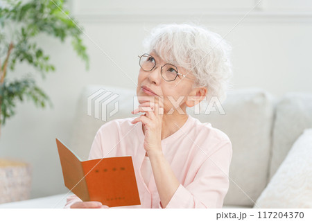 年金手帳を見るシニア女性 117204370