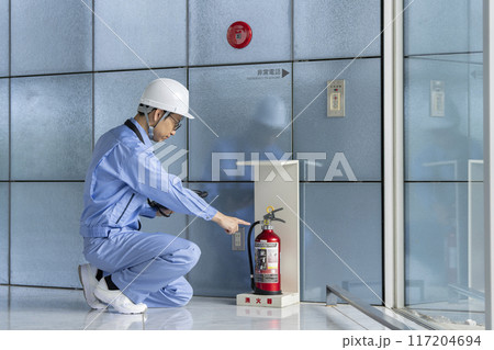消火器の点検をする作業服の男性　ビルメンテナンス　イメージ 117204694