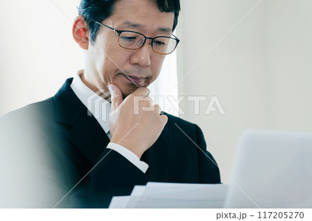 書類を見て悩むビジネスマン 書類を見て悩むビジネスマン 117205270