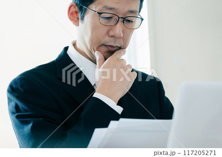 書類を見て悩むビジネスマン 117205271