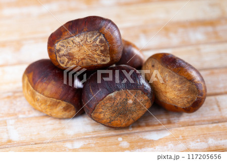 Unpeeled edible sweet chestnuts on wooden background Unpeeled edible sweet chestnuts on wooden background 117205656