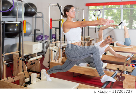 Young woman doing stretching on pilates reformer 117205727