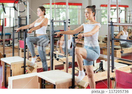 Young woman engaged in leg workouts on combo chair Young woman engaged in leg workouts on combo chair 117205736