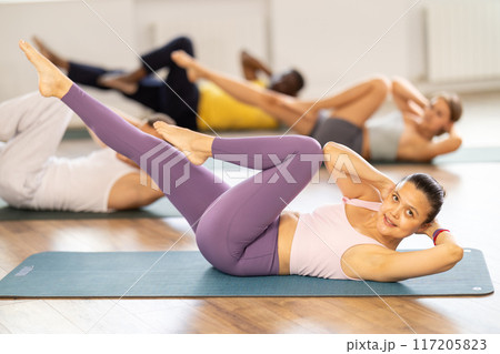 Asian woman performs exercises to strengthen abdominal muscles during group multinational workout Asian woman performs exercises to strengthen abdominal muscles during group multinational workout 117205823
