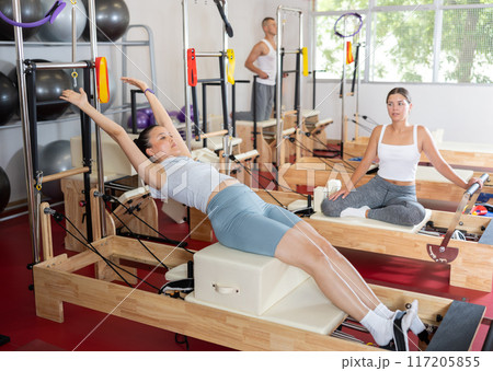 Young girl doing press exercises on reformer device 117205855