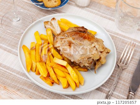 Baked pork shank with side dish of fried potatoes on plate Baked pork shank with side dish of fried potatoes on plate 117205857